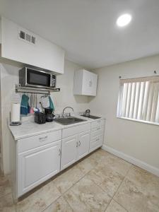 a white kitchen with a sink and a microwave at Amazing guest unit central location in St. Petersburg