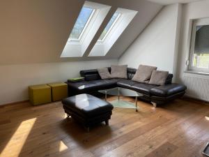 uma sala de estar com um sofá de couro preto e janelas em Ferienwohnung Igerc em Feistritz ob Bleiburg