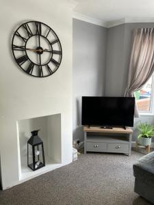 een woonkamer met een grote klok en een tv bij House for Contractors and Families in Aldershot