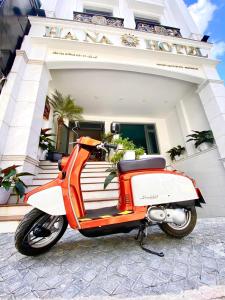 an orange and white scooter parked in front of a building at Hạ Na Hotel Đà Lạt in Da Lat