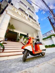 an orange scooter parked in front of a building at Hạ Na Hotel Đà Lạt in Da Lat