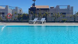 卡萊塔德菲斯泰的住宿－Sunny Luxury Apartment with two-level terrace, two swimming pools, next to golf course，两把蓝色椅子坐在游泳池旁