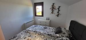 a bedroom with a bed with a comforter and a window at La Cabra Trepadora in Neril