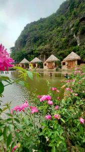 um grupo de cabanas e flores em frente a um lago em Hang Mua Eco Garden em Xuân Sơn