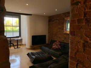 a living room with a couch and a flat screen tv at Lavish Apartment at Montpellier Gardens in Cheltenham