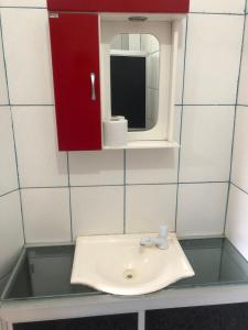 a bathroom sink with a red cabinet and a mirror at Pousada Ponta de Areia in Itaparica