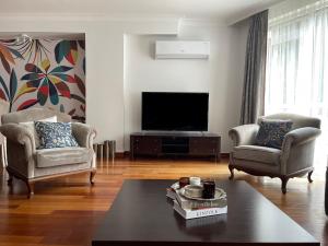 a living room with two chairs and a flat screen tv at Secure, Spacious, and Eclectic 1 to 3 Bedroom Apartments w Pool, Garden, Private Parking, Tennis Basketball Football Courts and Concierge close to Istinye Park, Turkish Tennis Federation, and Acibadem Maslak in Istanbul