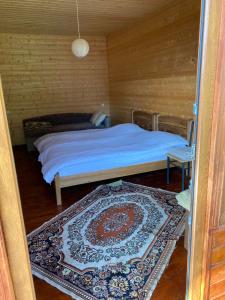 1 dormitorio con cama y alfombra en el suelo en B & B Juta, en Kazbegi
