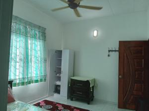 een slaapkamer met een plafondventilator en een raam bij Narayana Illam in Nilai