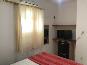 Schlafzimmer mit einem Bett, einem TV und einem Fenster in der Unterkunft Pousada Ponta de Areia in Itaparica Town