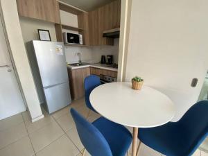 Confortable Apartamento para 3 في سانتياغو: مطبخ بطاولة بيضاء وكراسي زرقاء