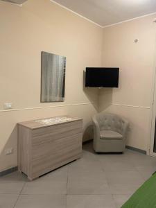 アヴォラにあるLa Scoglieraの壁に椅子とテレビが備わる客室です。