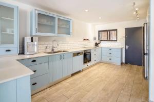 a kitchen with white cabinets and a wooden floor at YalaRent Cliff side villa with private pool in Eilat
