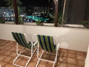 dos sillas verdes y blancas sentadas frente a una ventana en 2 Bedrooms apartment swimming pool, en Monastir