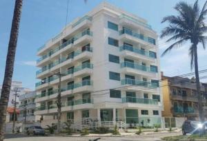 a large white building with palm trees in front of it at Apartamento de 3 quartos com vista para o mar in Arraial do Cabo