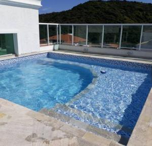 a swimming pool with blue water in front of a building at Apartamento de 3 quartos com vista para o mar in Arraial do Cabo