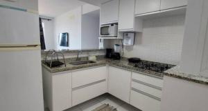 a kitchen with white cabinets and a sink and a microwave at Apartamento de 3 quartos com vista para o mar in Arraial do Cabo
