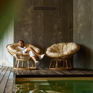 a man sitting in two chairs next to a pool at Quinta do Pedregal Hotel & Spa in Vila Nova de Gaia