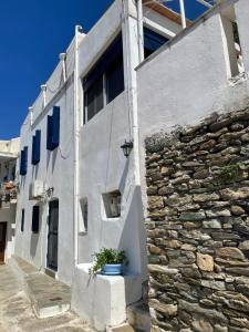 a white building with a stone wall and a plant at The Great Balcony in Ioulis