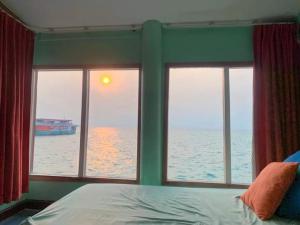 a bedroom with a view of the ocean through windows at Lareena Resort Koh Larn Pattaya in Ko Larn