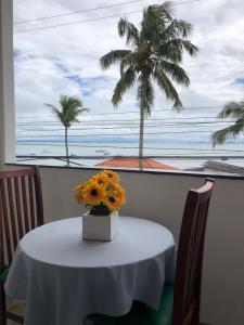 a table with flowers on it with a palm tree at Pousada Ponta de Areia in Itaparica