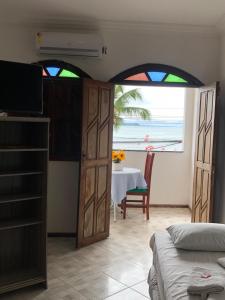 a bedroom with a room with a table with a view of the ocean at Pousada Ponta de Areia in Itaparica Town