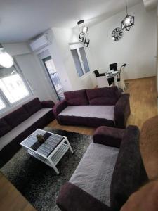 a living room with purple couches and a table at Tea Apartment in Kumanovo