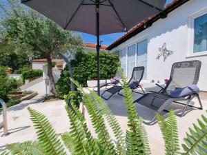 2 sedie e un ombrellone su un patio di Villa Ilaria a Bol