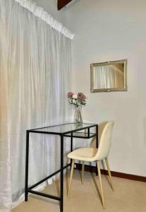 una mesa y una silla con un jarrón de flores en Separate entry cozy Guesthouse en Hillcrest