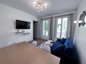 a living room with a blue couch and a table at Paris 18 - 6P - 2BR - Appartement cosy moderne équipé in Paris