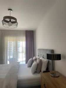 a white bedroom with a large bed with a window at Dora City Apartament in Cluj-Napoca