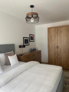 1 dormitorio con cama blanca y armario de madera en Dora City Apartament, en Cluj-Napoca