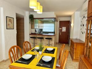 uma sala de jantar com uma mesa amarela e cadeiras em Domuum Holidays - DMS III POOL em Salou