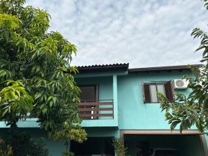 una casa azul con árboles delante de ella en Apto familiar em Cachoeirinha-RS, en Cachoeirinha