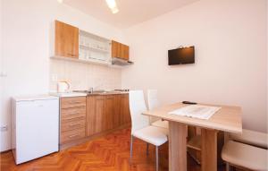 克拉帕尼島的住宿－Cozy Apartment In Sibenik With Kitchen，厨房配有桌子和白色冰箱。