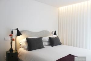 a bedroom with a white bed with pillows and two lamps at Azores Essence - Coliseu in Ponta Delgada