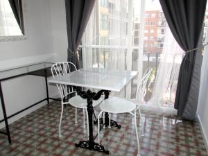 - une table et des chaises dans une chambre avec fenêtre dans l'établissement Pensió Cerdanya, à Barcelone