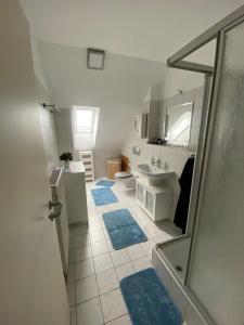 a bathroom with a shower and blue rugs on the floor at Dachgeschoss Apartment mit Ausblick in Halle an der Saale