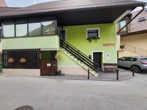 ein grünes Haus mit einer Treppe davor in der Unterkunft Apartma CIK in Bovec