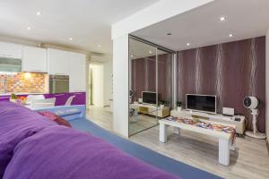 a bedroom with a purple bed and a living room at Alpha loft 1BR apartment in center in Zadar