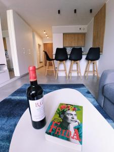 uma garrafa de vinho sentada numa mesa com um livro em Lulu Apartments - Apartament FRIDA blisko morza - Resort Kołobrzeg parking i basen z sauną w cenie em Kolobrzeg