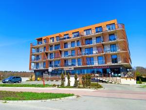 um grande edifício com um carro estacionado em frente em Lulu Apartments - Apartament FRIDA blisko morza - Resort Kołobrzeg parking i basen z sauną w cenie em Kolobrzeg