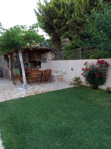 een patio met een tafel en stoelen in een tuin bij Villa Tsios in Artemida