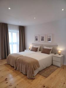 a bedroom with a large white bed with two lamps at Flor da Laranjeira in Elvas