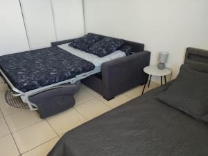 - une chambre avec un lit, un canapé et une table dans l'établissement Studio Zen Urban climatisé proche aéroport Saint Denis, à Sainte-Clotilde