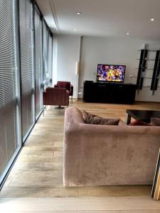 a living room with a couch and a flat screen tv at Stylish 2BRM with nice city view in London