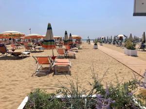una spiaggia con sedie e ombrelloni sulla sabbia di Villa Wanda 2 a Bibione