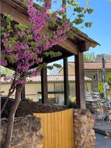 un árbol con flores púrpuras junto a una valla de madera en Le relais de Romane Logement 3 étoiles tout confort, piscine en Saint Antonin du Var