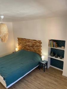 Un dormitorio con una cama verde y una pared de ladrillo en Le relais de Romane Logement 3 étoiles tout confort, piscine en Saint Antonin du Var