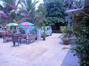 un patio con mesas, sillas y sombrillas en Beach Xaviers Guest House Colva, en Colva